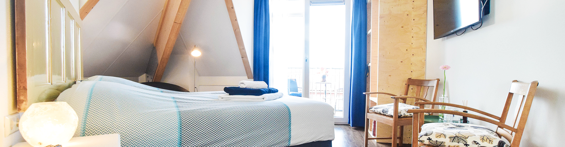 Een van onze kamers; een opgemaakt bed met opgevouwen handdoeken