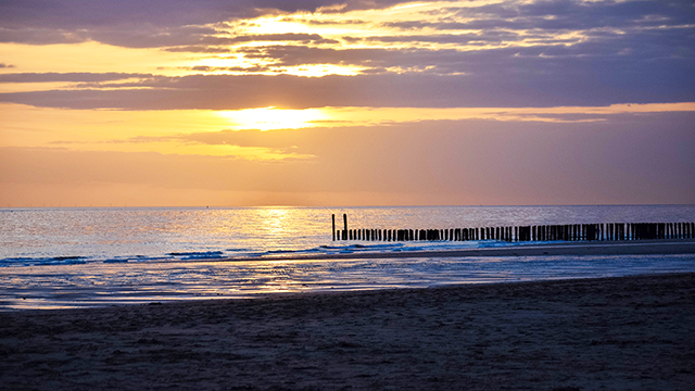 Ondergaande zon boven de zee met een paalhoofd